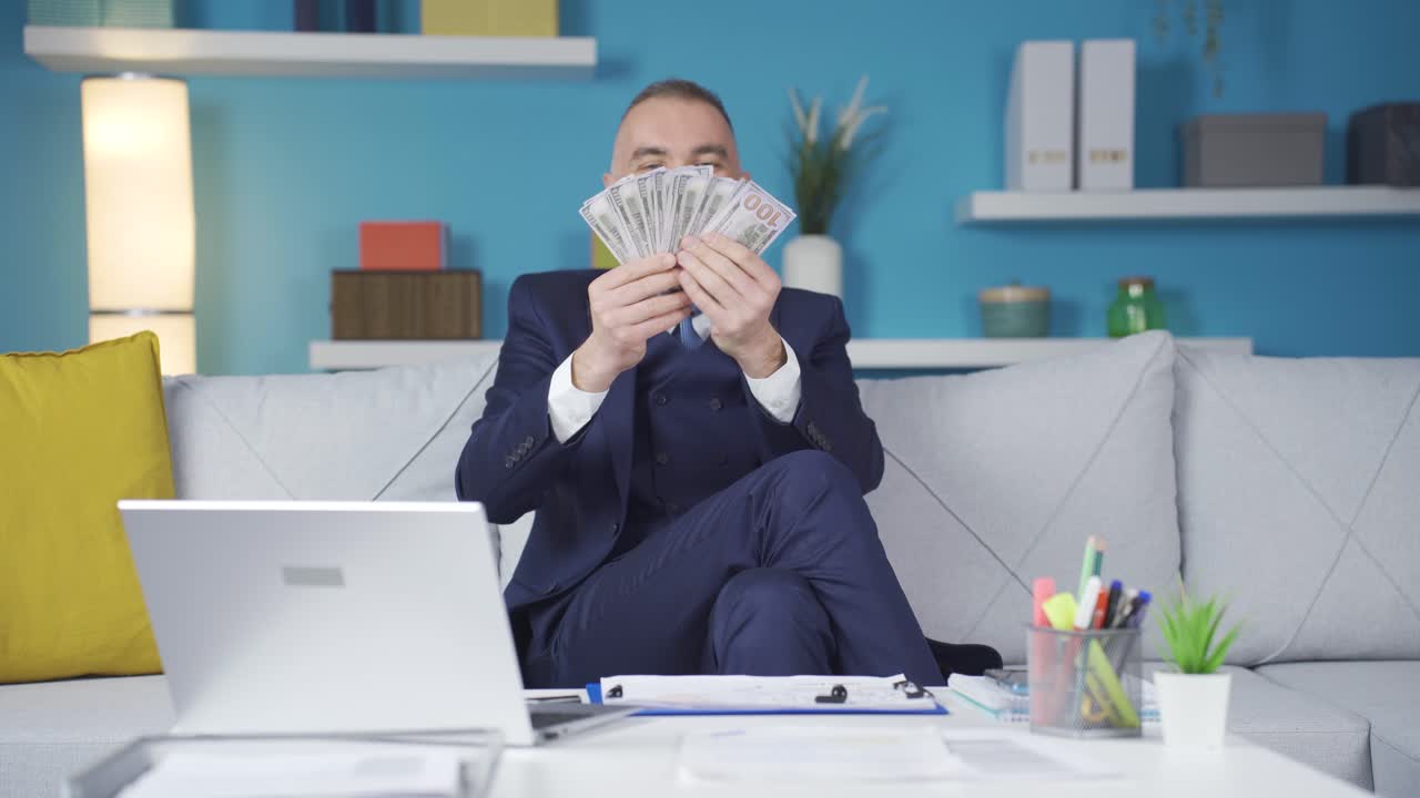 부유한 사업가입니다. 그는 집에서 달러로 놀고 행복합니다.