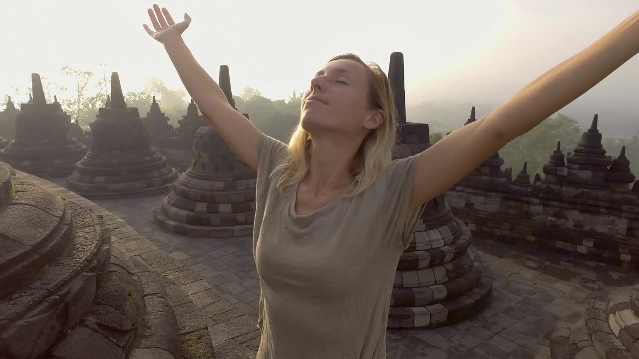 4K-resoluution video matkustavasta tytöstä syleilemässä auringonnousua Borobudurin temppelillä, Indonesiassa. Ihmiset löytävät Aasian -konsepti