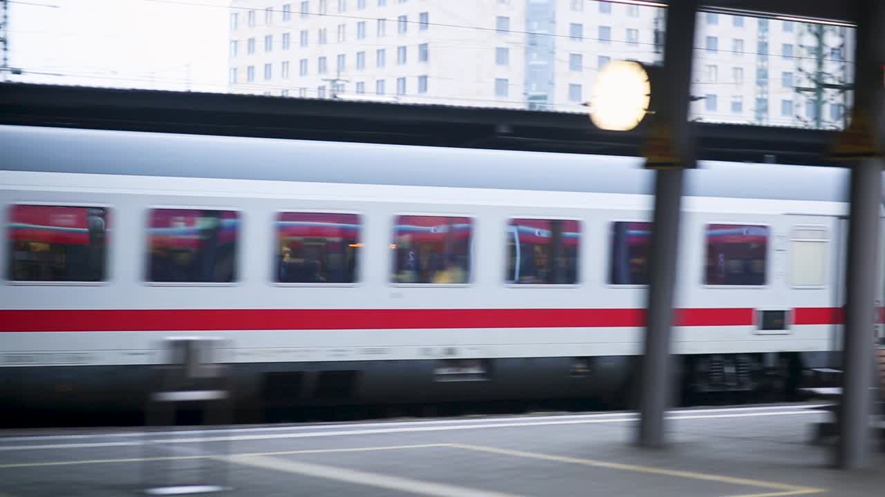 People waiting at a bustling train station as a train speeds past