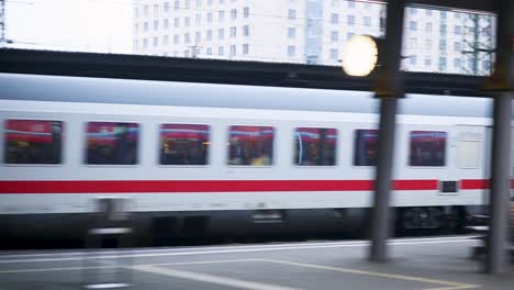 people waiting at a bustling train station as a train speeds past