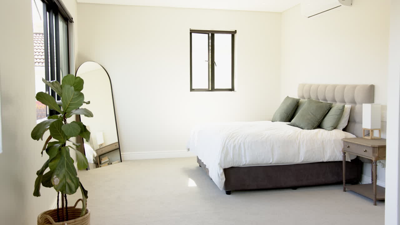 Modern bedroom with large mirror, potted plant, and neatly made bed, copy space