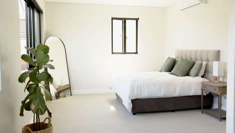 modern bedroom with large mirror, potted plant, and neatly made bed, copy space