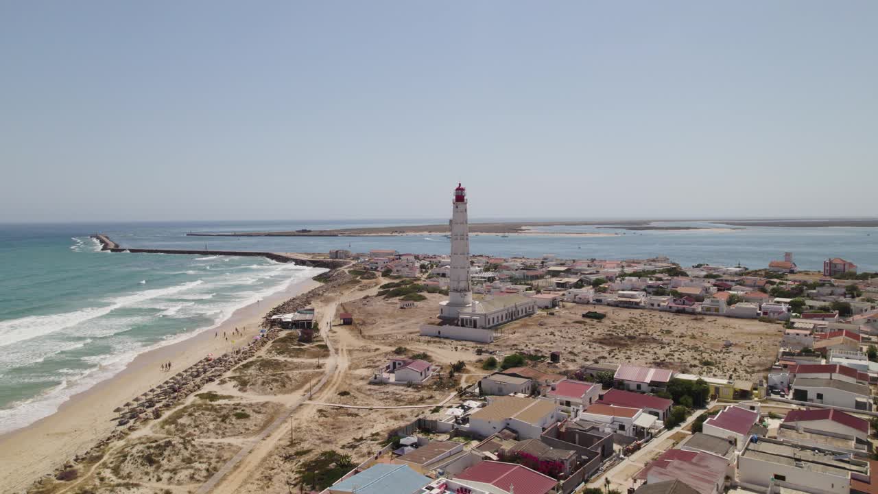 tomada aérea en órbita de isla do farol, pintoresco pueblo costero con faro histórico, olhao