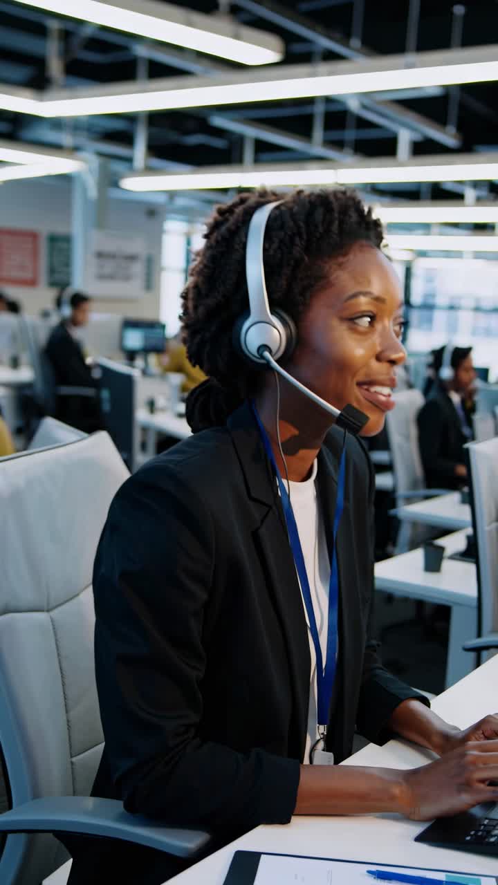 Un operatore sorridente dell'assistenza clienti in un call center, ripreso lateralmente