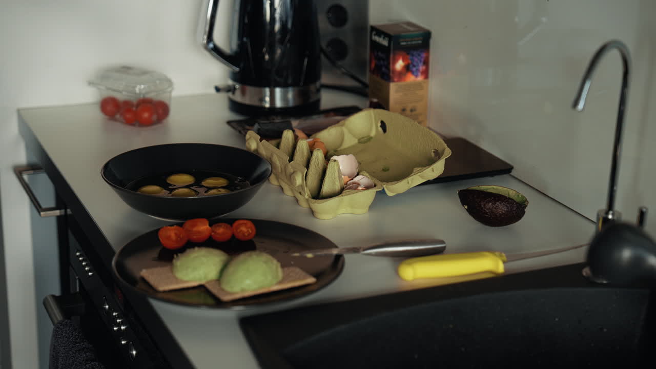 A man preparing a homemade breakfast on a kitchen counter, mixing eggs and slicing avocado and tomatoes. A cozy morning scene showing healthy lifestyle and mindful home cooking