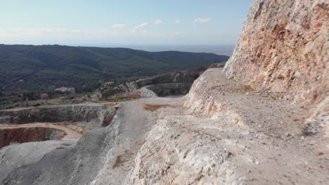 Aerial-view-close-quarry-steps-revealing-trucks-unload-soil-to-restore-quarry-sunny-day