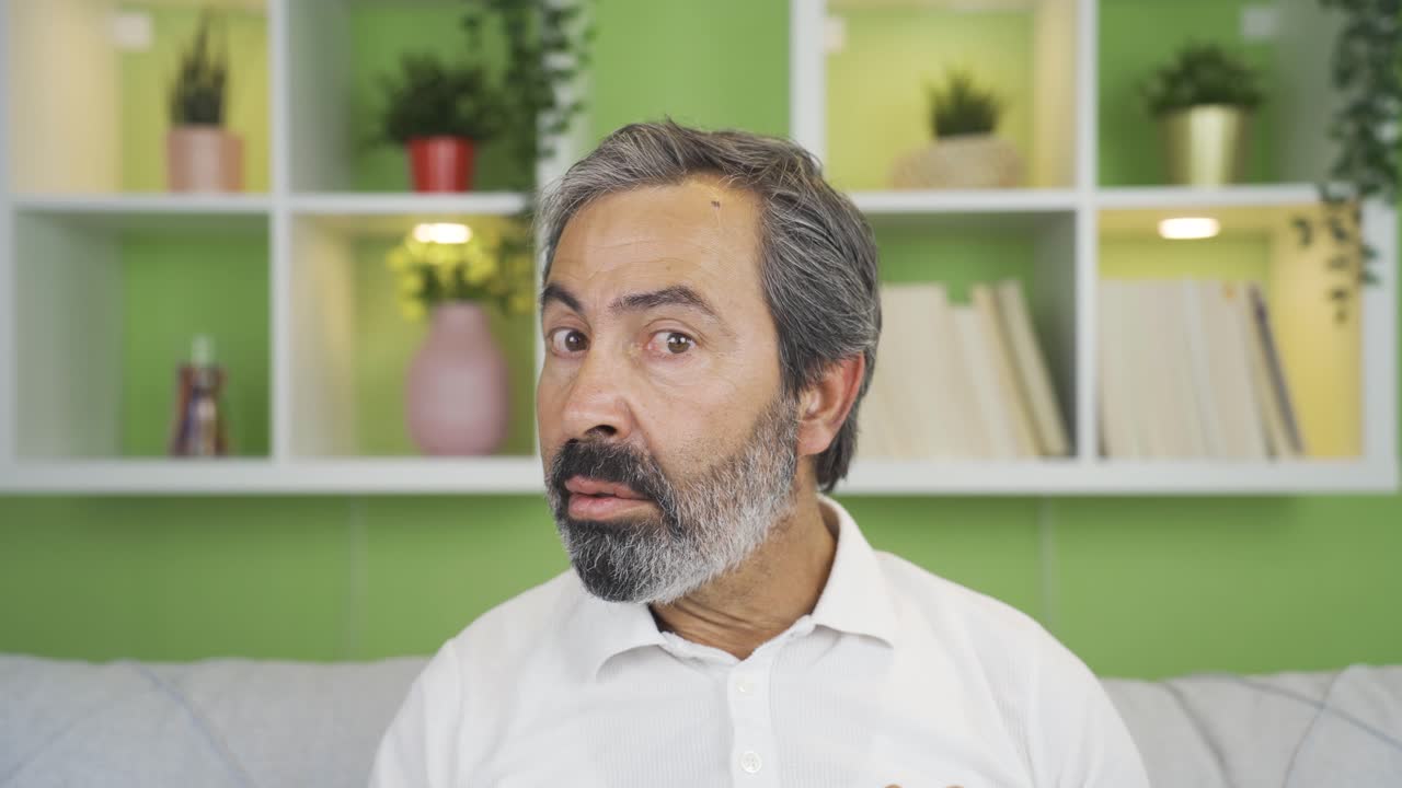 Close-up mature man looks at camera with fear and panic.