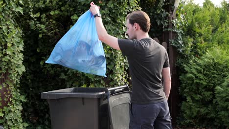 Varón-Caucásico-Sacando-Basura-En-Una-Bolsa-De-Plástico-A-La-Papelera-En-El-Jardín