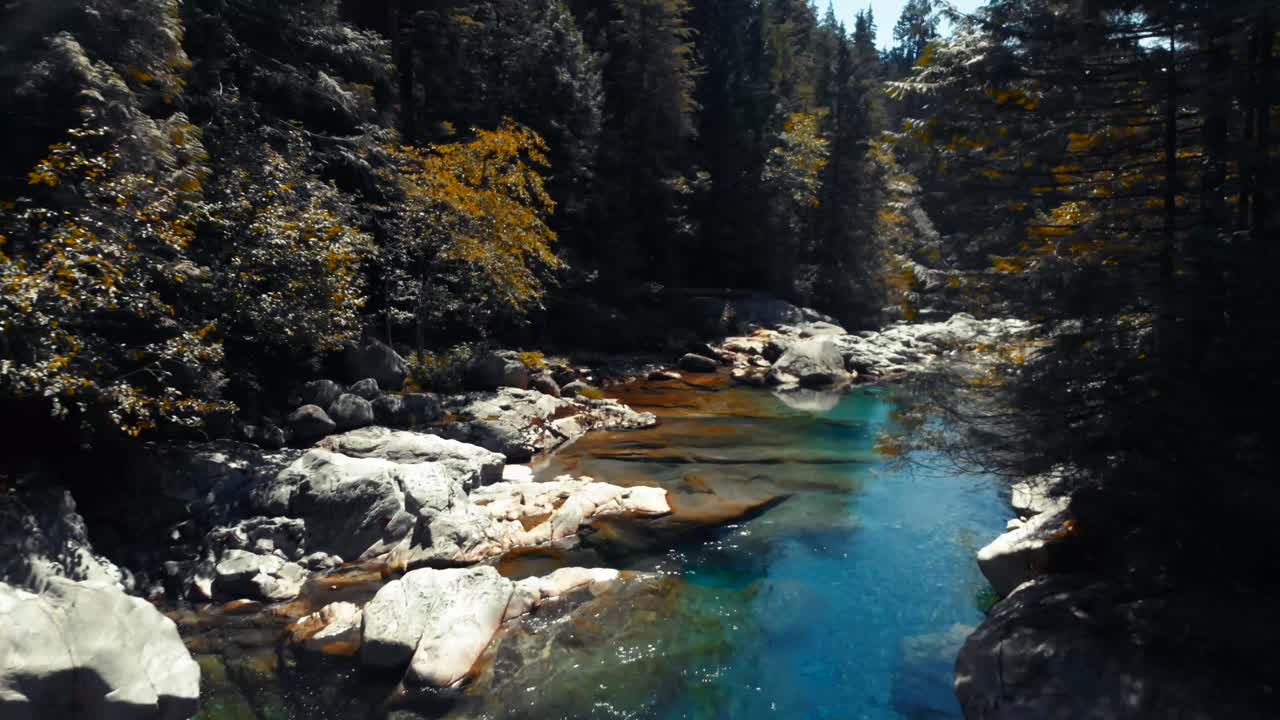 A bright blue pond in the mountains reflecting the sun's shining rays
