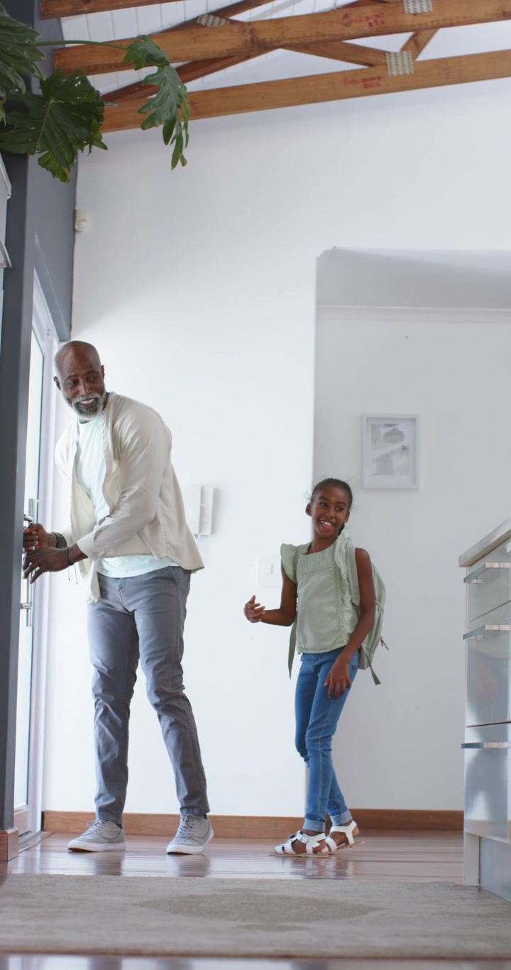 Vertical video: African American father ushering teen daughter with backpack into foyer returning