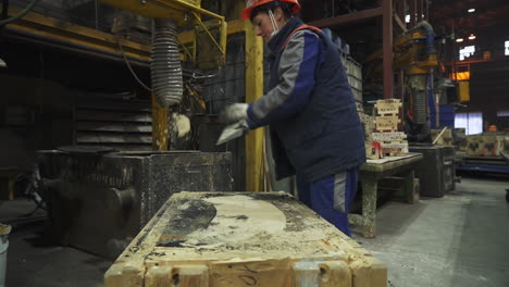 worker cleaning mold in foundry