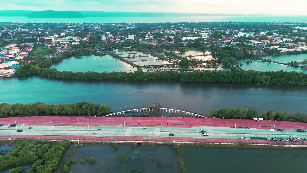Scenic drone footage of a Philippine city with rivers, mangroves, and a pedestrian bridge. Ideal for travel, lifestyle, urban planning, and environmental projects