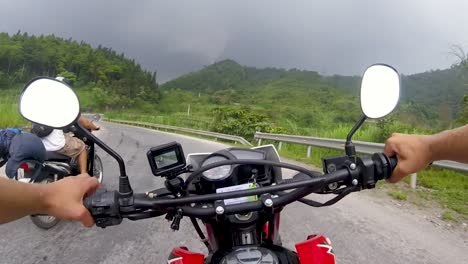 一个男人骑着摩托车沿着<unk>曲的道路在越南北部山脉的暴风雨天气1