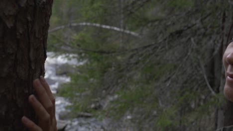 Girl-looking-at-a-tree-besides-a-river-in-the-forest