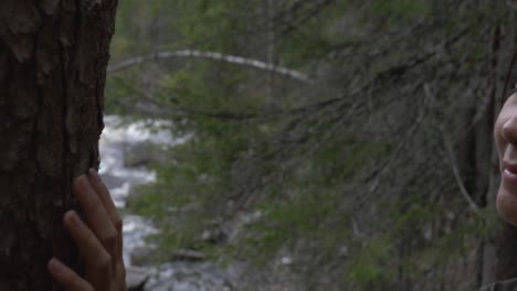 chica mirando un árbol junto a un río en el bosque