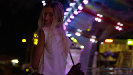 young blonde woman models for camera at showground carnival at night