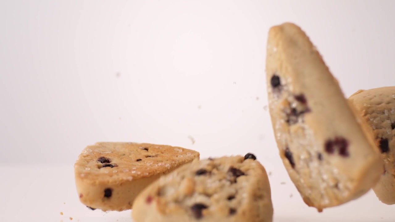 Crumbly fruit-studded scones dropping and bouncing across white seamless backdrop in high speed slow motion. mothers day brunch posts, tea shop ads, weekend brunch videos.