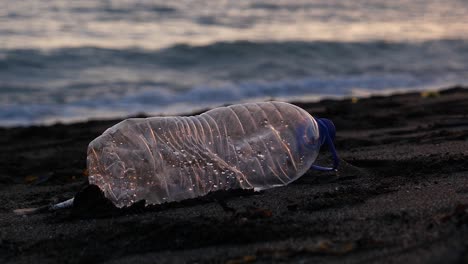 a discarded plastic bottle on a sandy beach at dusk