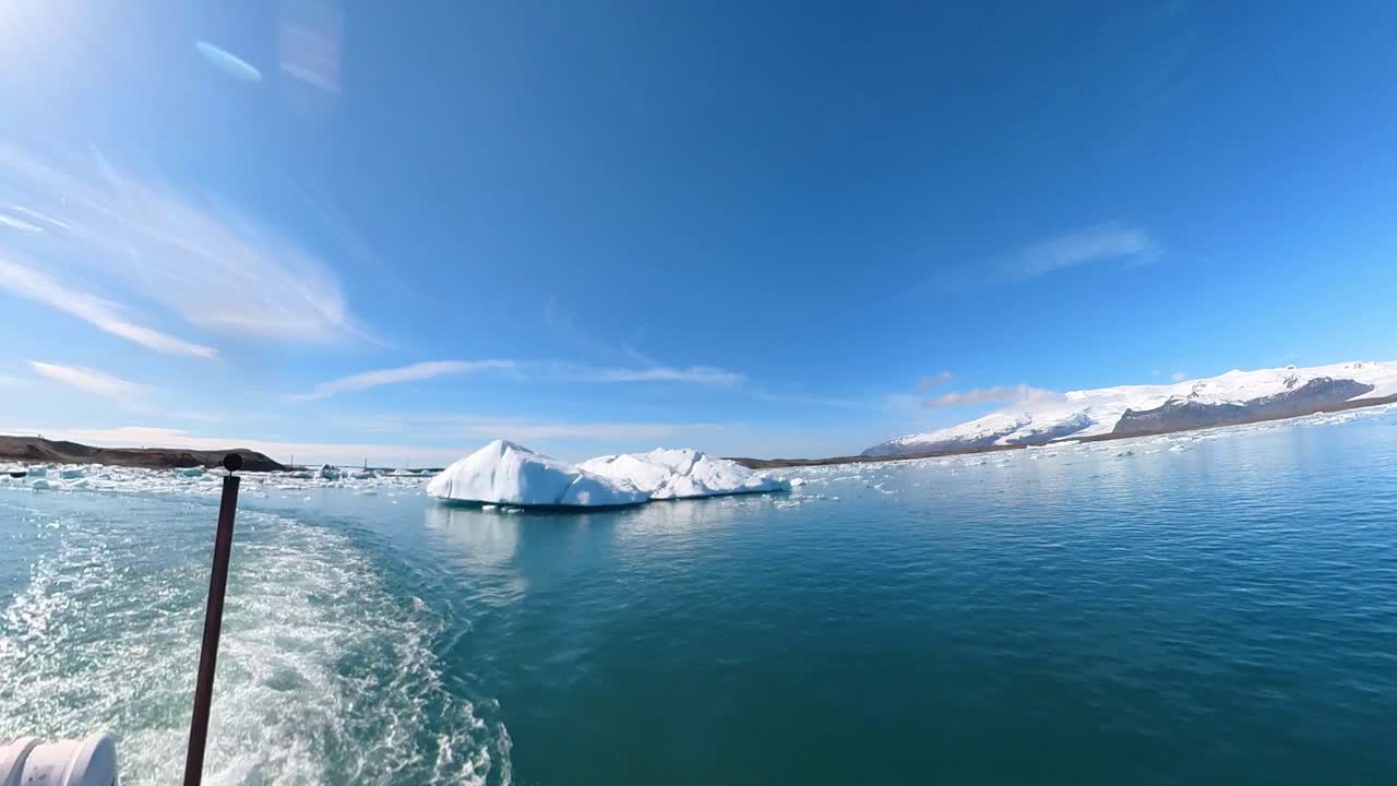 A picture-perfect moment, a graceful boat sails through Iceland's snow-encrusted mountains, reflecting serenity and majesty.