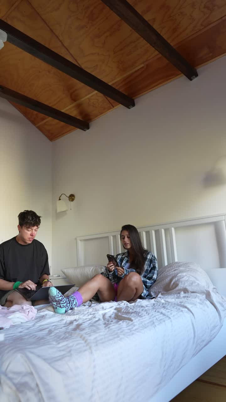 Casal Relaxando no Quarto com Laptops e Celulares