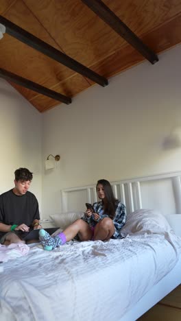 couple relaxing in bedroom with laptops and phones