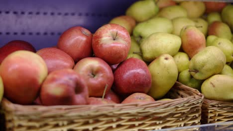 female hand in glove picks fruits apples from basket in supermarket