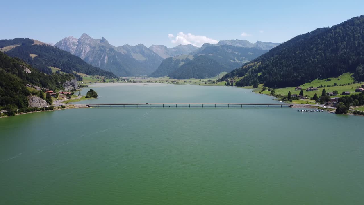 뒤에 산 범위와 호수 sihlsee 위의 다리에서 이동하는 자동차의 공중 샷