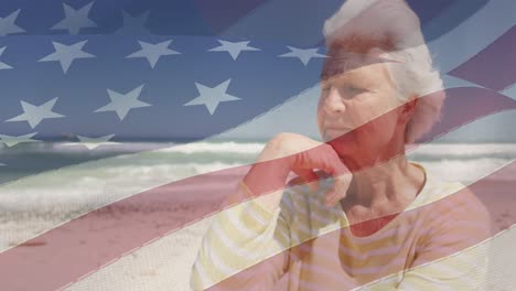 Animation-of-senior-caucasian-woman-sitting-on-beach-over-flag-of-united-states-of-america