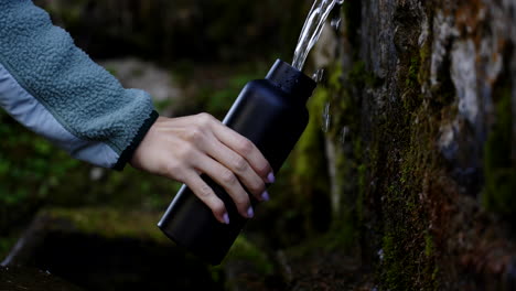 filling a water bottle from a spring