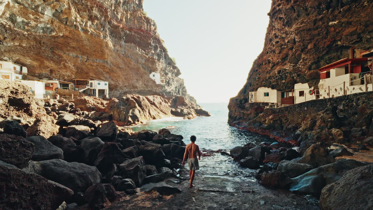Back shot of a young man enjoying the view of the Porís de Candelaria in Palma Island, Canary Islands, Spain. Fishing village inside a rugged coastline cave. Hidden Gem.