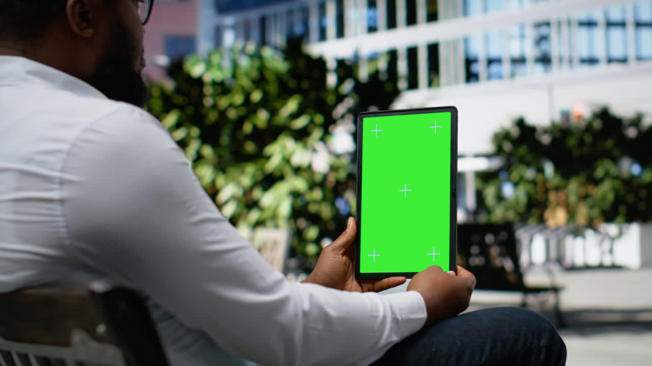 Vertical green screen with black man sitting relaxed on a bench