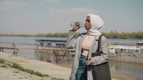 arabian black lady drinks mineral water at boat station