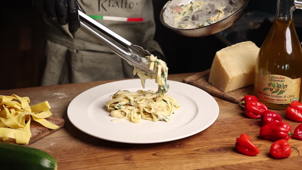 Koch serviert frisch gekochte cremige Pasta auf einem weißen Teller