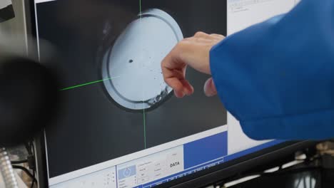 hand pointing to cross section of glass fiber under microscope on screen in laboratory