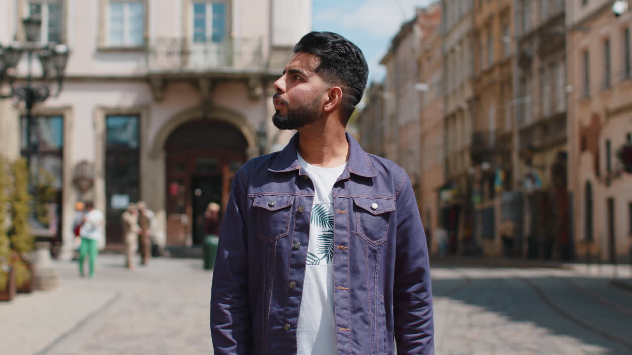 Portrait of young indian man tourist walking in urban city street smiling having positive good mood