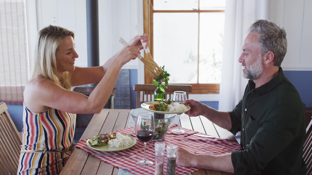 feliz pareja caucásica madura sonriendo, hablando y disfrutando de la comida juntos