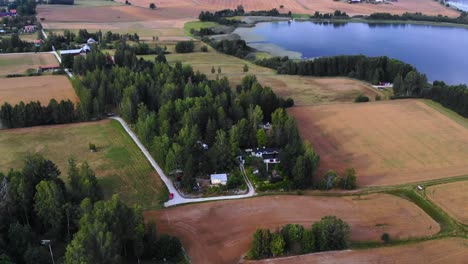 imágenes de drones de algunas casas junto a los campos y un lago en suecia