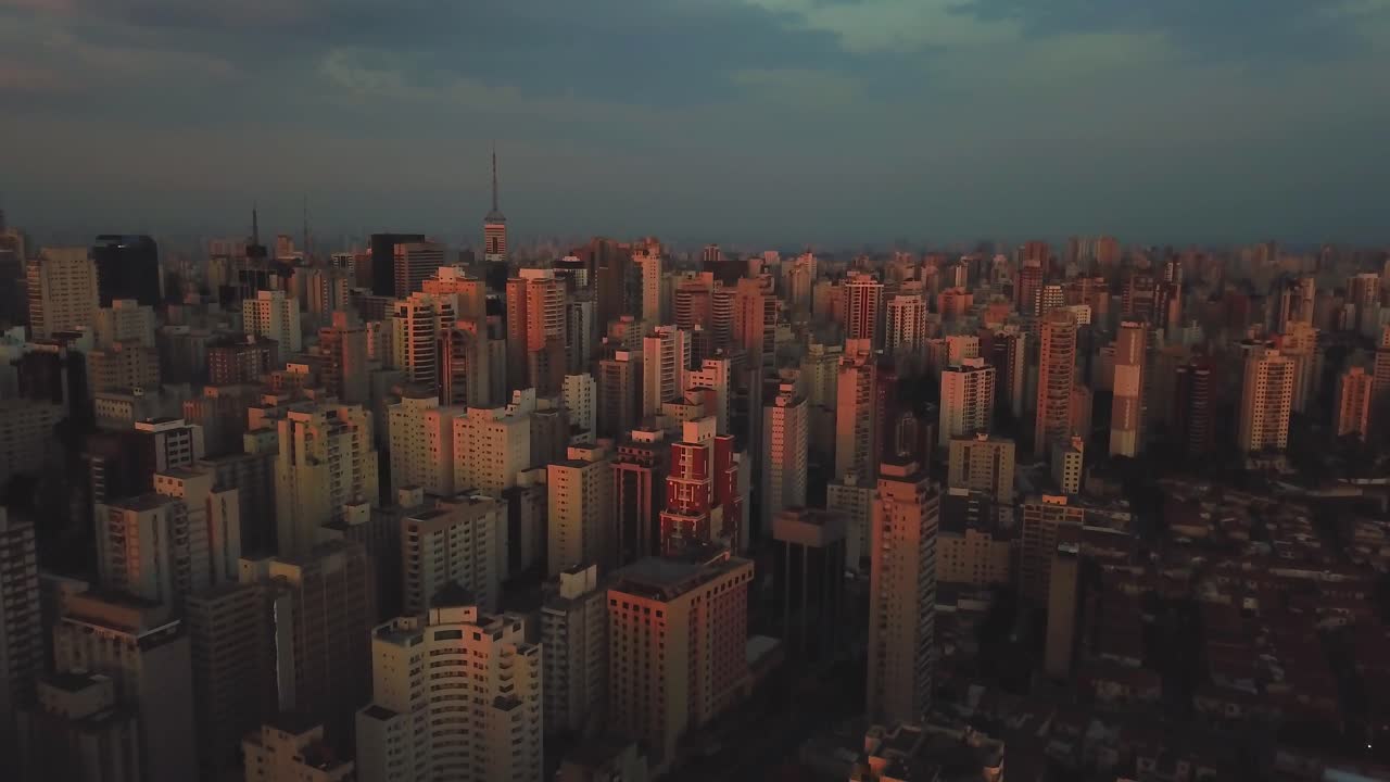 Belo pôr do sol no centro de São Paulo, Brasil, com imagem aérea de céu rosado e edifícios.