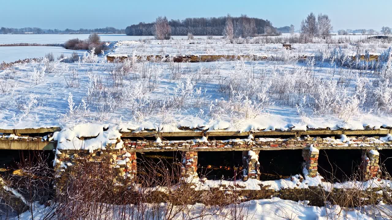 Lumiset rauniot talvisella pellolla kirkkaan sinisen taivaan alla