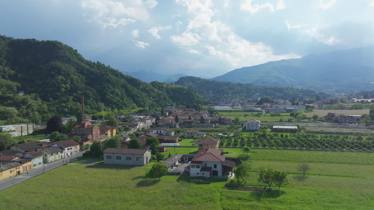 Captivating rising aerial footage unveils a beautiful community nestled in a serene valley amidst towering mountains