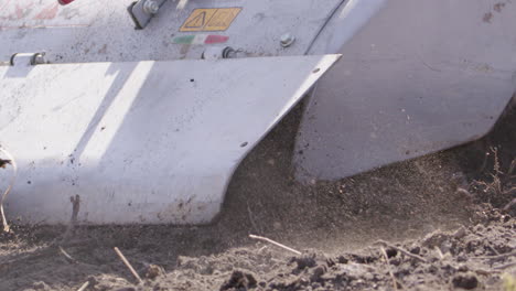 blades of a rototiller working the land, agriculture, slow motion close up