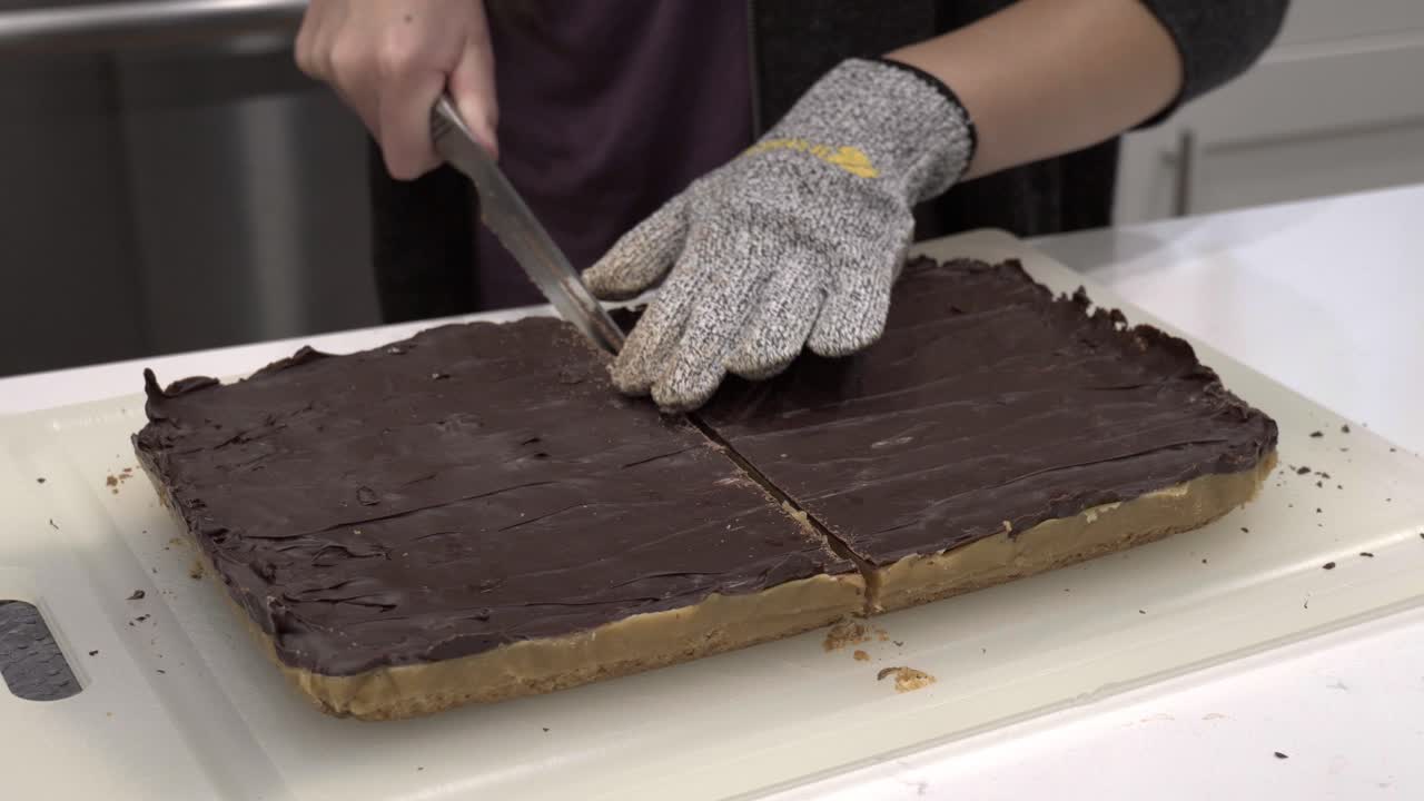 A young girl cuts the finished millionaire shortbread cookie into small pieces-1