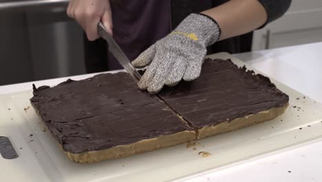 a young girl cuts the finished millionaire shortbread cookie into small pieces-1