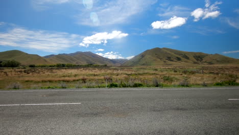 a car crosses the scene in front with incredible new zealand mountain landscape in the background on a beautiful sunny day