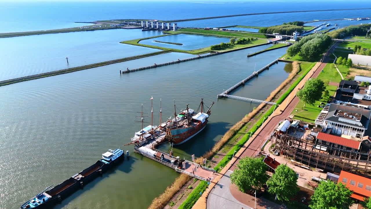 Reconstruction ships standing at the berth. Drone rises above the water revealing view on the museum Batavialand in Lelystad, The Netherlands.