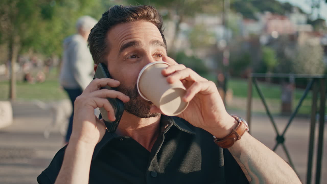 un macho sonriente hablando en una celda compartiendo buenas noticias. ciudad de primer plano. hombre bebiendo café.