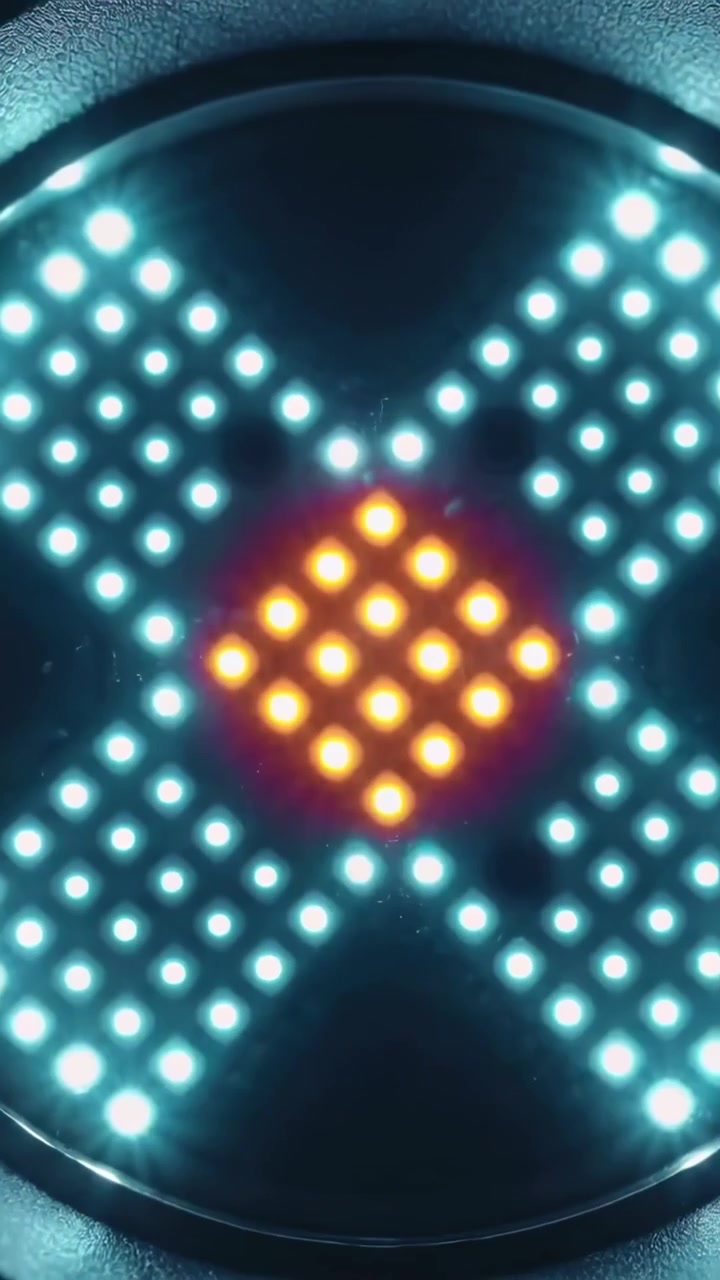 Vertikální video: Kulatý LED panel měnící azurové X na oranžové jádro, růžově pulzující v tmavém detailu