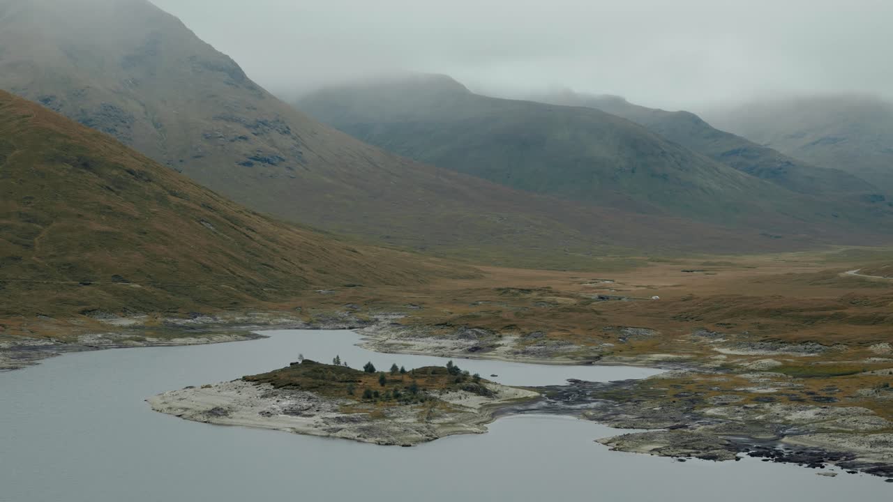 Circling right shot of Loch Cluanie and towering Highlands shrouded in mist