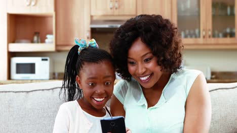 Mother-and-daughter-using-mobile-phone-in-living-room-4k