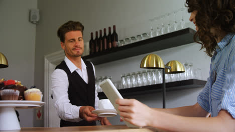 waiter serving coffee to costumer at counter